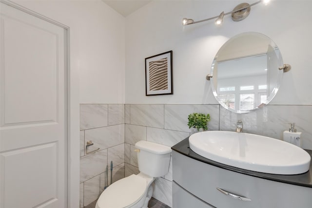 bathroom with vanity, toilet, and tile walls