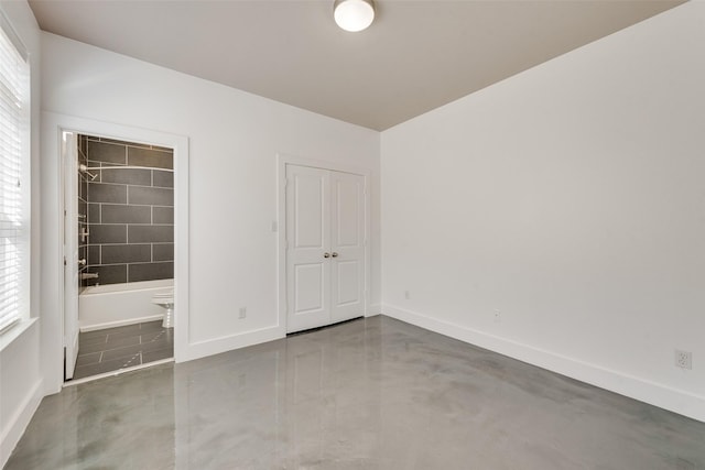 unfurnished bedroom featuring a closet, multiple windows, and ensuite bathroom