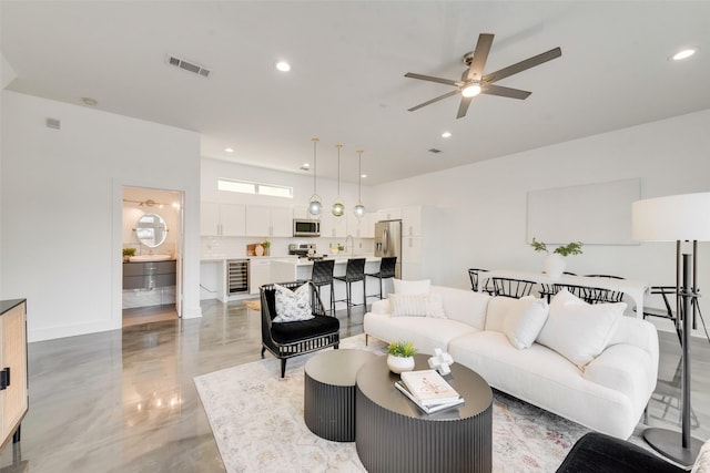 living room with wine cooler, ceiling fan, and sink