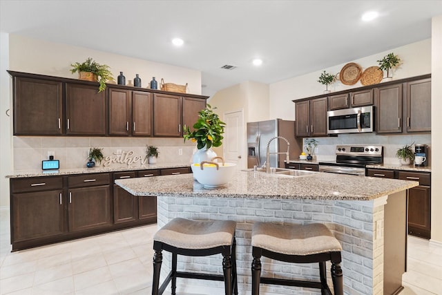 kitchen with stainless steel appliances, an island with sink, and a breakfast bar area