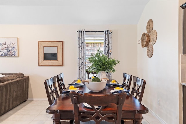 dining area with light tile patterned floors and vaulted ceiling