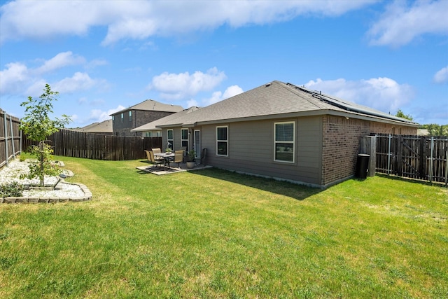 back of house with a lawn, a patio area, and solar panels