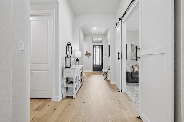 hallway featuring a barn door and light hardwood / wood-style flooring