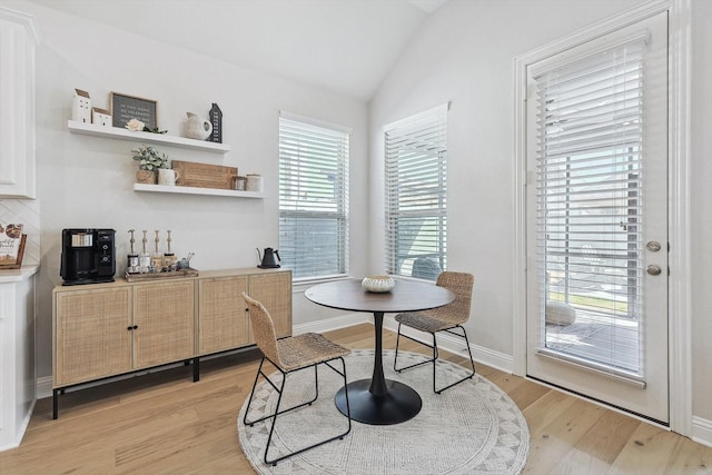 dining space with light hardwood / wood-style floors and lofted ceiling