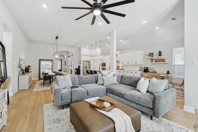 living room featuring ceiling fan with notable chandelier and light hardwood / wood-style floors