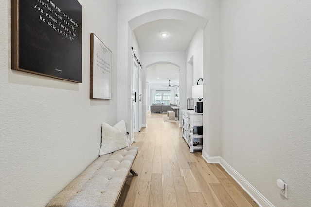 hall with a barn door and light hardwood / wood-style flooring