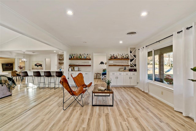 interior space featuring light hardwood / wood-style flooring, bar, and ornamental molding