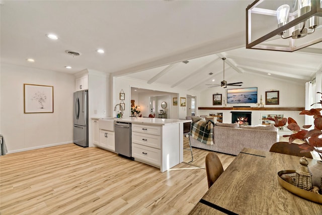 kitchen featuring a breakfast bar area, white cabinetry, lofted ceiling with beams, appliances with stainless steel finishes, and kitchen peninsula