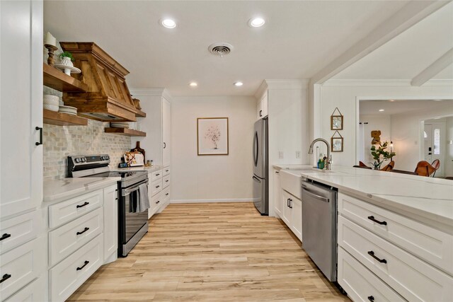 kitchen featuring white cabinetry, light stone counters, stainless steel appliances, light hardwood / wood-style floors, and decorative backsplash