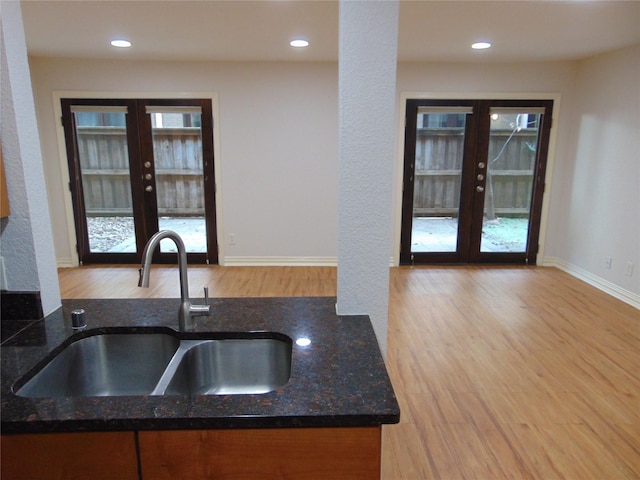 kitchen featuring french doors, sink, light hardwood / wood-style flooring, and dark stone counters