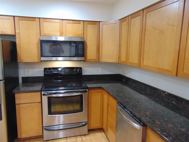 kitchen featuring appliances with stainless steel finishes and dark stone counters