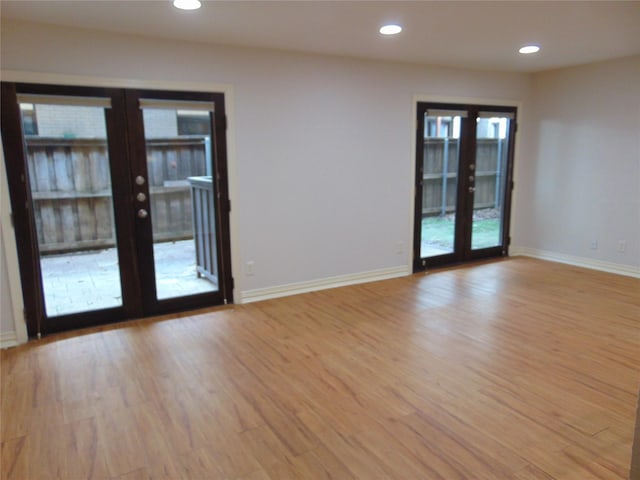 empty room with light hardwood / wood-style floors and french doors