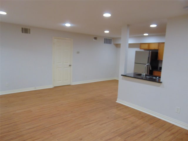 unfurnished living room with sink and light hardwood / wood-style flooring