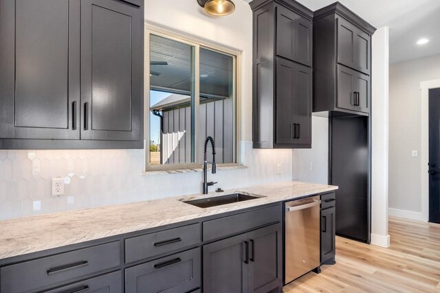 kitchen featuring light stone countertops, stainless steel dishwasher, sink, light hardwood / wood-style flooring, and gray cabinets