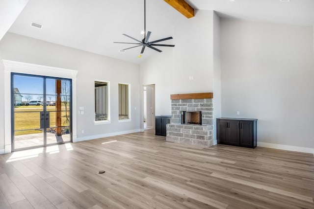 unfurnished living room featuring light wood-type flooring, ceiling fan, beam ceiling, high vaulted ceiling, and a fireplace