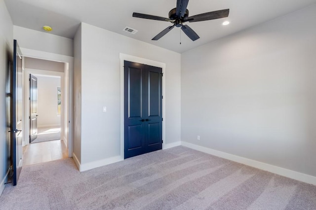 unfurnished bedroom featuring light carpet, a closet, and ceiling fan