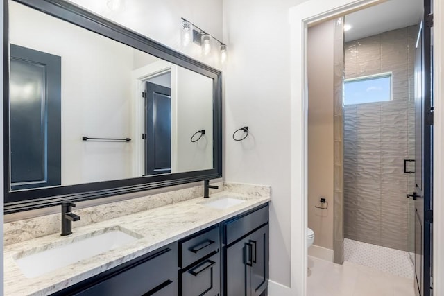 bathroom with a tile shower, vanity, and toilet