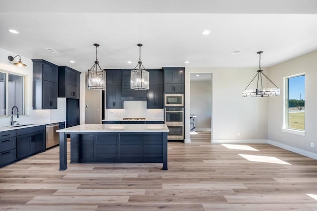 kitchen with a chandelier, stainless steel appliances, a center island, and sink