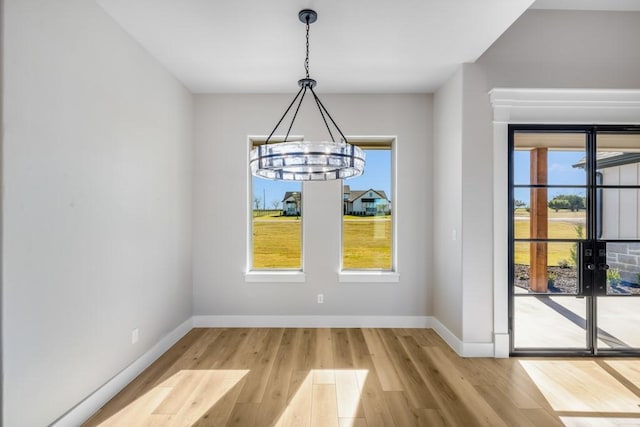 unfurnished dining area featuring hardwood / wood-style flooring and an inviting chandelier