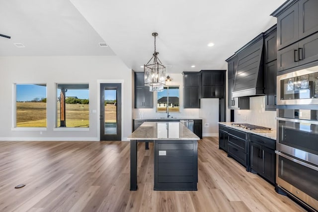 kitchen featuring light stone countertops, tasteful backsplash, light hardwood / wood-style flooring, decorative light fixtures, and a kitchen island