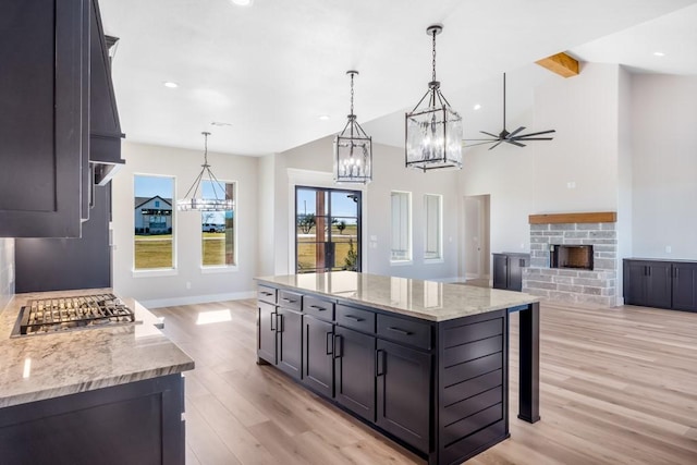 kitchen featuring light stone counters, a fireplace, a spacious island, and decorative light fixtures