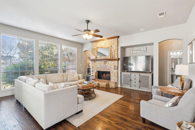 living room featuring dark wood-type flooring, ceiling fan, plenty of natural light, and a fireplace