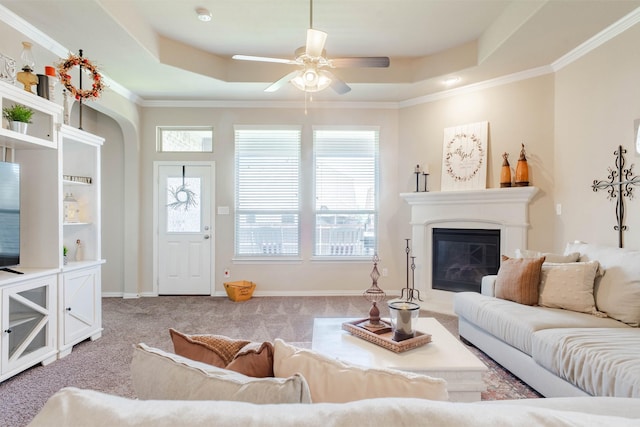 carpeted living room featuring a tray ceiling, ceiling fan, and ornamental molding