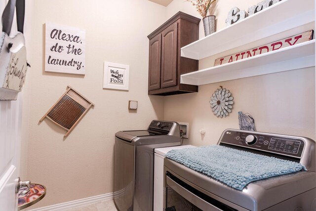 clothes washing area featuring washer and dryer and cabinets