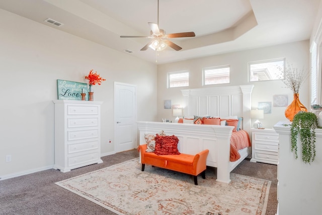 carpeted bedroom featuring a tray ceiling and ceiling fan