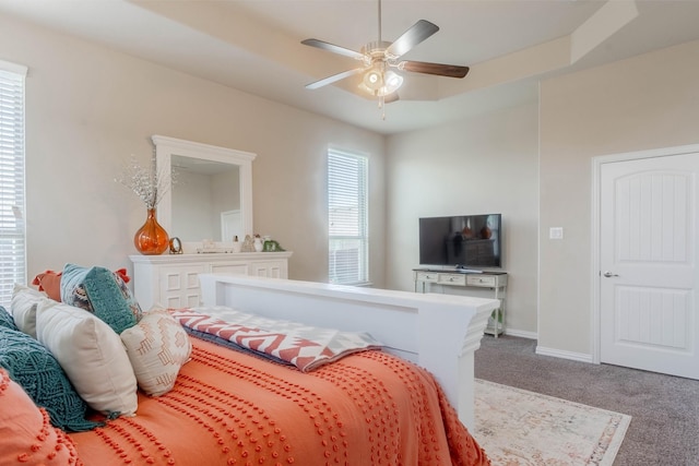 bedroom with carpet flooring, a tray ceiling, and ceiling fan