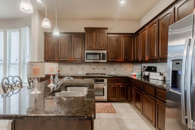 kitchen featuring dark stone countertops, dark brown cabinetry, sink, and stainless steel appliances