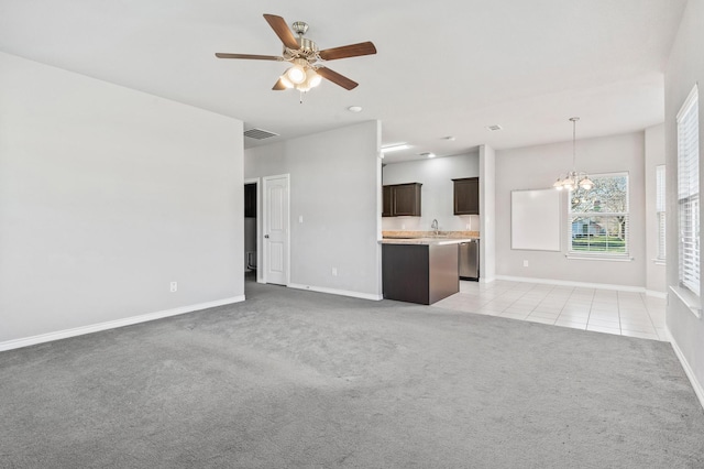 unfurnished living room featuring visible vents, light carpet, ceiling fan with notable chandelier, a sink, and light tile patterned floors