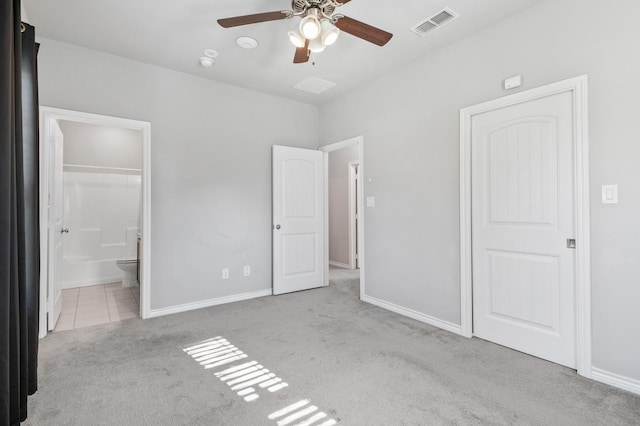 unfurnished bedroom with a closet, light colored carpet, ceiling fan, and ensuite bathroom