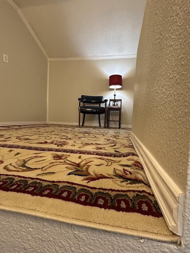 bedroom with vaulted ceiling, crown molding, baseboards, and a textured wall