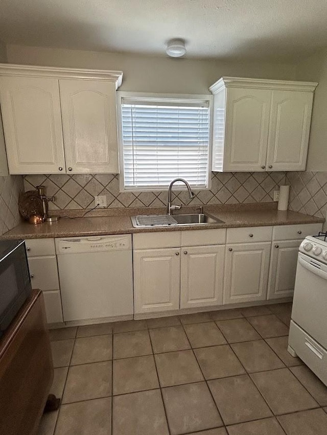 kitchen with light tile patterned floors, decorative backsplash, white cabinets, white appliances, and a sink