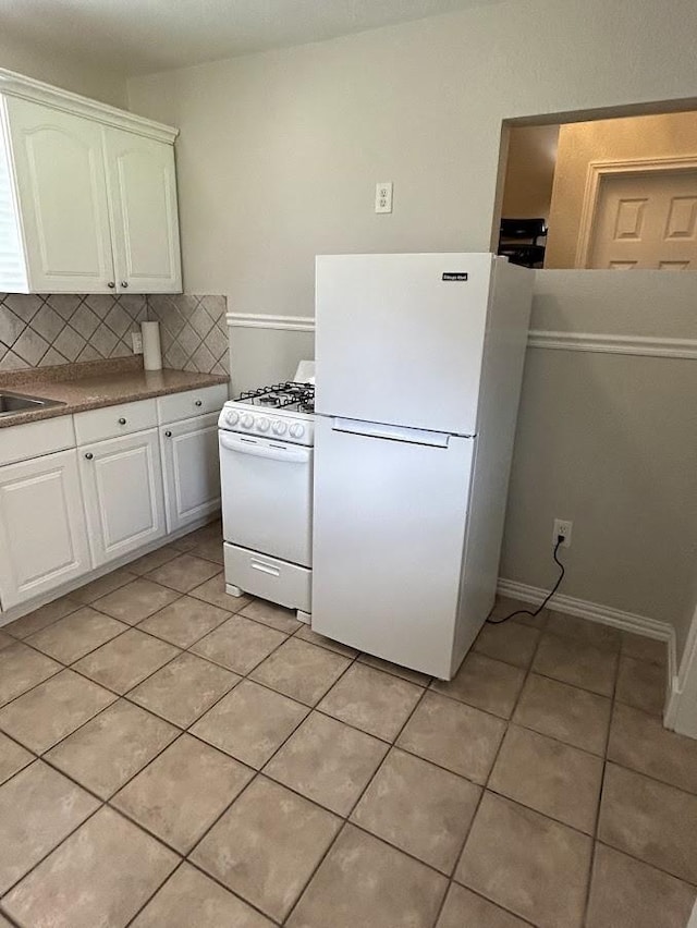 kitchen featuring white appliances, light tile patterned flooring, and white cabinets