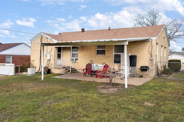 back of house featuring brick siding, a patio area, a lawn, and fence