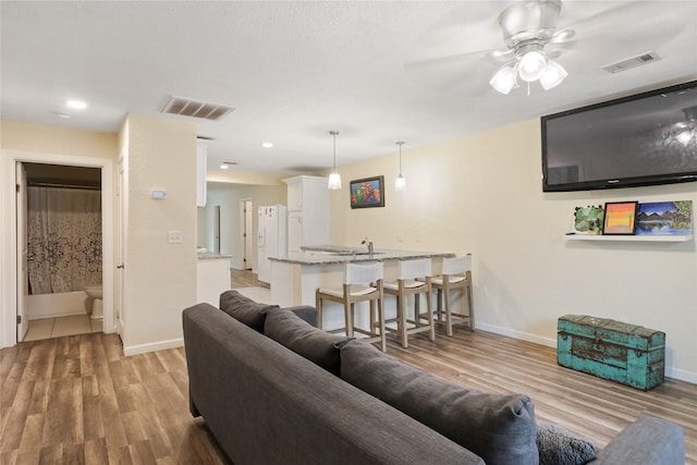 living room with ceiling fan, light hardwood / wood-style flooring, and sink