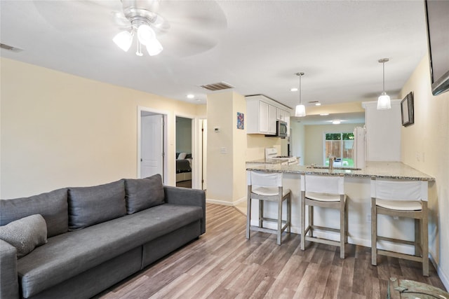 living room featuring ceiling fan, sink, and light hardwood / wood-style floors