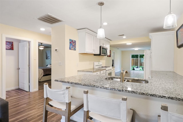 kitchen with sink, hanging light fixtures, kitchen peninsula, white appliances, and white cabinets