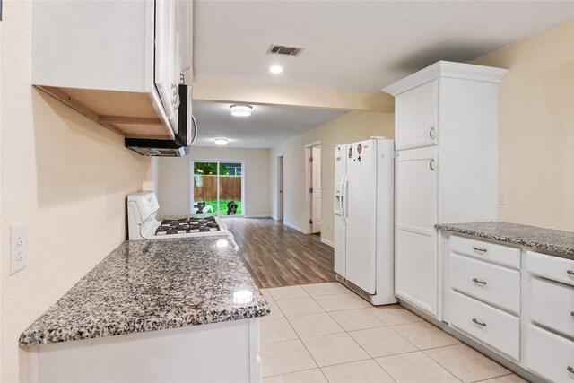 kitchen featuring white cabinets, light stone countertops, white appliances, and light tile patterned floors