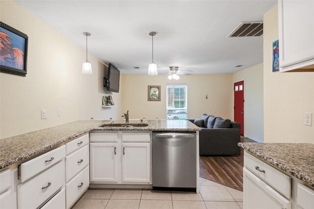 kitchen with sink, light tile patterned floors, stainless steel dishwasher, kitchen peninsula, and white cabinets