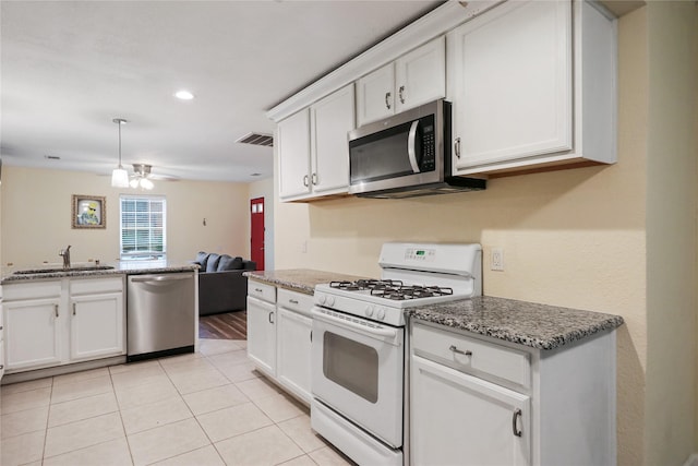 kitchen featuring white cabinetry, sink, ceiling fan, stainless steel appliances, and dark stone counters