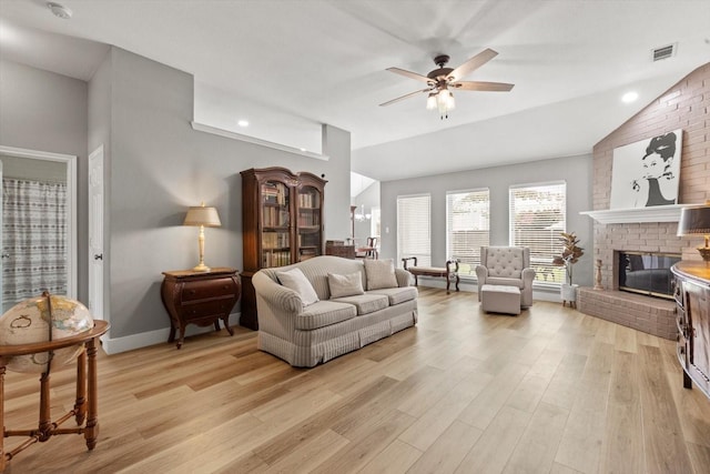 living room with ceiling fan, light hardwood / wood-style floors, lofted ceiling, and a brick fireplace