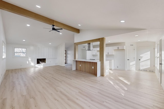 unfurnished living room featuring vaulted ceiling with beams, ceiling fan, a fireplace, and light hardwood / wood-style flooring