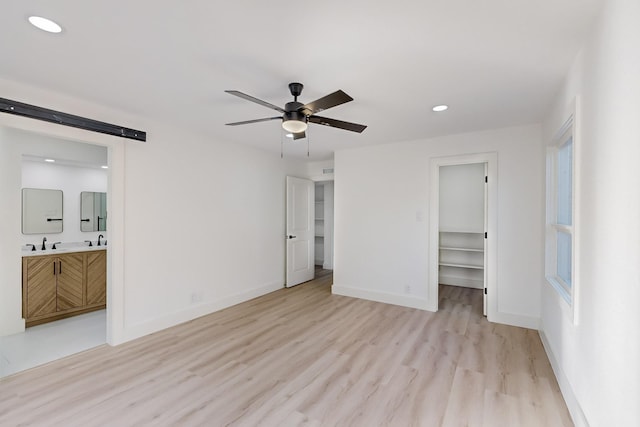 unfurnished bedroom with ceiling fan, a walk in closet, light hardwood / wood-style flooring, and ensuite bath