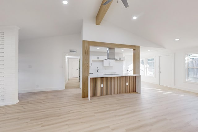 unfurnished living room with vaulted ceiling with beams, ceiling fan, a wealth of natural light, and light wood-type flooring