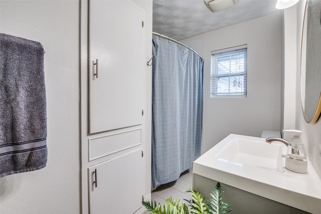 bathroom with tile patterned flooring, vanity, and walk in shower