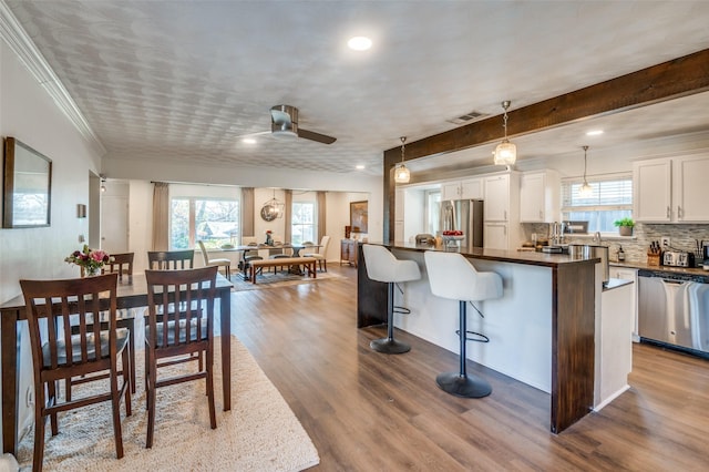 kitchen with white cabinets, hanging light fixtures, ceiling fan, a kitchen island, and stainless steel appliances