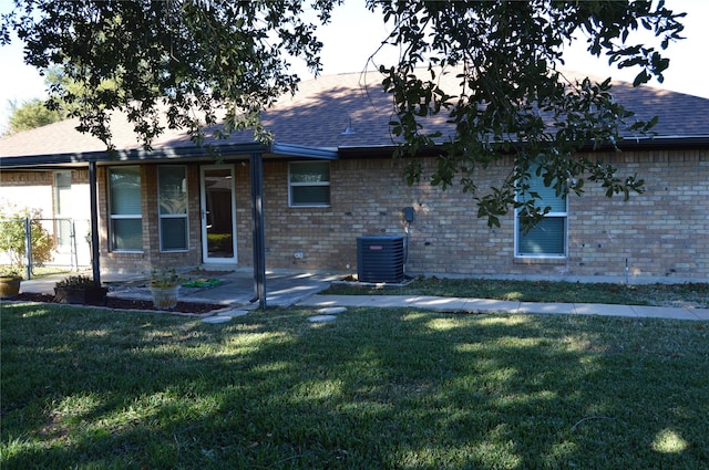 view of front of house with a patio area, a front yard, and central air condition unit